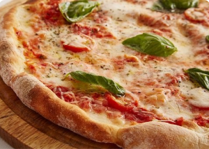 Une pizza maison avec une croûte dorée, garnie de tomates, fromage et basilic, représentant une recette spécialement conçue pour les personnes atteintes de rectocolite hémorragique (RCH), maladie de Crohn, et autres MICI.