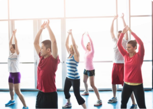 Groep mensen die aan het sporten zijn in een fitnessruimte, symboliseert hoe fit blijven kan helpen bij het beheer van colitis ulcerosa en de ziekte van Crohn.